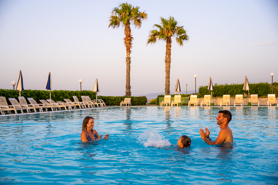Una famiglia gioca in piscina durante una vacanza ad agosto